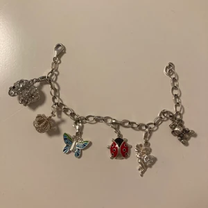 Berlock armband  - Berlock armband i silver. Omkrets ca 17,5 centimeter. (Diamant elefant, diamant krona, blå fjäril, röd nyckelpiga, ängel med diamanthjärta och silvrig nalle)