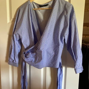 Omlottopp från Zara - En vit/blå-randig omlottopp från Zara. Använd en gång. Storlek M men passar även L då den är justerbar. 