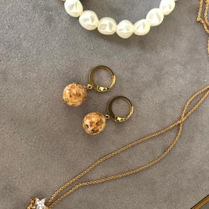 Guldiga örhängen - Handgjorda guldiga örhängen med brun/guldig pärla, som är helt nya! 