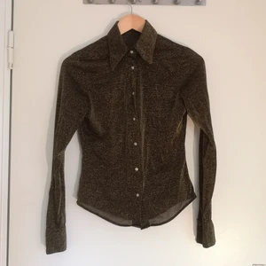 Glittrig skjorta strl S - Fin skjorta med vackra tryckknappar, köpt på second hand. Den skiftar i brunt, guld och koppar. 