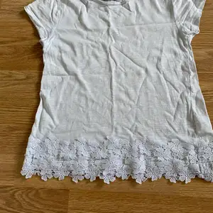 Vit t-shirt med blomm spätts längst ner, har använt ( lite genomskinlig )