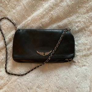 Zadig & Voltaire väska - Säljer min älskade Zadig väska som jag tyvärr inte får så mycket användning av längre! Den är använd men i bra skick, silvret på vingarna är lite skavt men inget man tänker på! Nypris ca 3500, båda banden, dustbag och tag medföljer💞