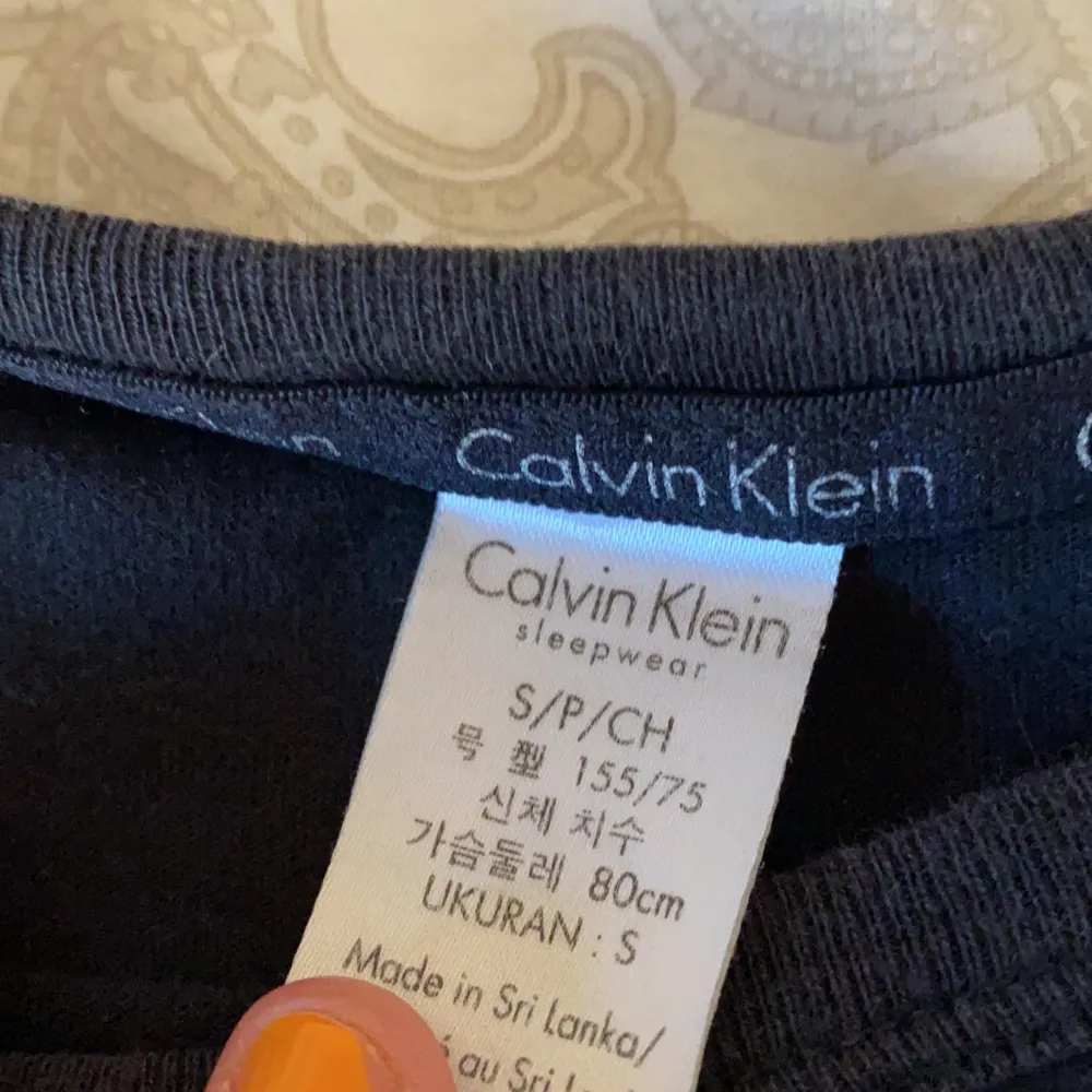 En svart Calvin Klein tröja som är synliga tecken på användning . En fläck uppe vid kragen och lite sliten text så därav priset. . T-shirts.