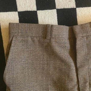 Rutiga kostymbyxor - Rutiga, brunbeiga kostymbyxor inköpta på en secondhandaffär i New York. Riktigt snyggt mönstrade, passar en som är 28-29 i midjan.