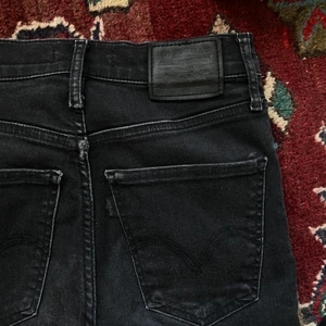 Levis jeans - Svarta högmidjade skinny jeans i modellen ”Mile High Super Skinny” använda en del men nu blivit försmå för mig. Har bleknat lite i färg och har en liten slitning på låret (se bild 2), därav priset 🌞