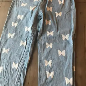 Ett par blå jean med vita fjärilar på. Knappen känns lös men den ska vara så. Köparen står för frakten 