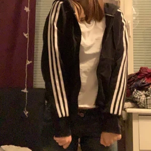 Adidas zip-hoodie - Säljer nu mina jättefina svarta adidas zip-hoodie med vita adidas ränder på armarna, storlek Xs men sitter bra på mig som vanligtvis köper S-M! Skriv privat för andra frågor🥰