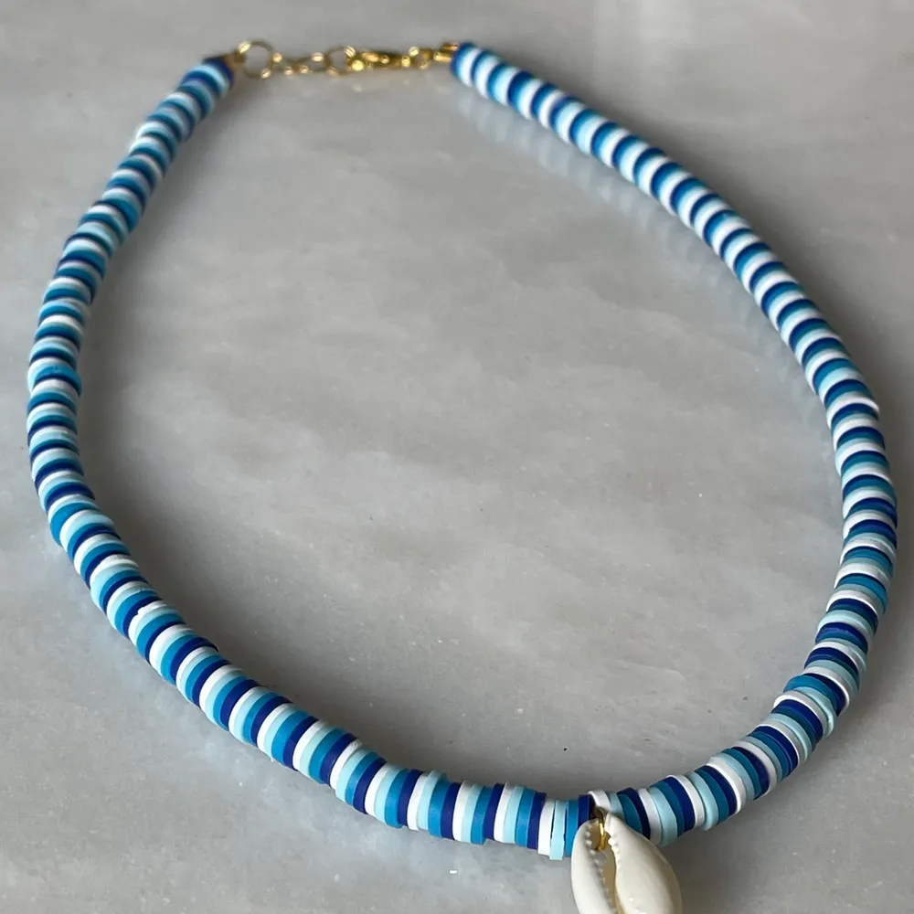 Ett superfint och trendigt halsband i olika blåa nyanser och med en vit färg. Ingår spänne och ringödlor så man kan justera det efter önskan. . Accessoarer.