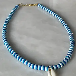 Ett superfint och trendigt halsband i olika blåa nyanser och med en vit färg. Ingår spänne och ringödlor så man kan justera det efter önskan. 