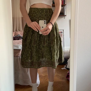 Grön mönstrad midikjol - Grön högmidjad kjol med mönster i brunt, grönt och gult. Storlek 38 men insydd så passar xs-s. Slutar under knäna på mig som är 165 cm. Finns dragkedja i sidan. Möts i Stockholm annars betalar köpare frakt. 