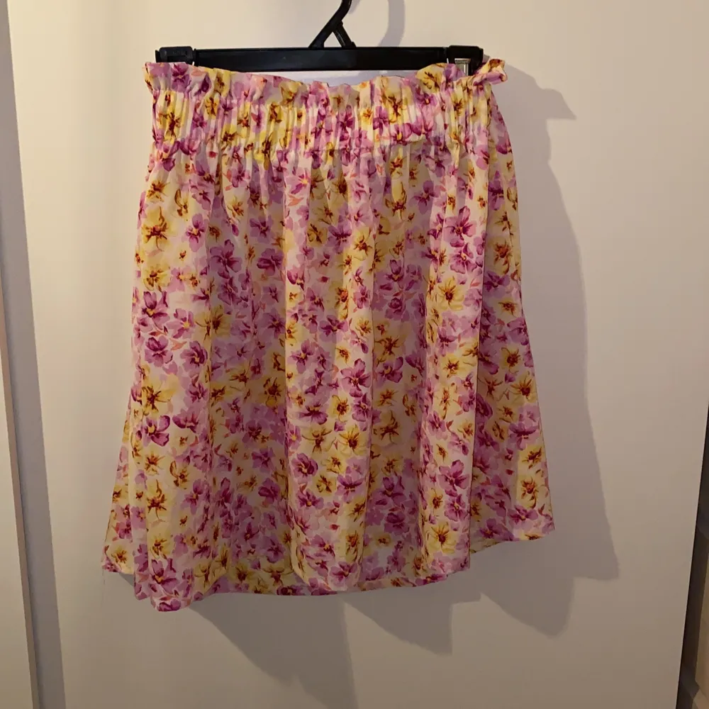 En rosa/lila och gulblommig kjol från bikbok. Inköpt för ca 1 och ett halvt år sedan men endast använd en gång då den är alldeles för stor i midjan. Storlek M men det är resår så passar säkert L oxå. Den har även fickor(!!!), hur bra? Säljes för 70kr. Kjolar.
