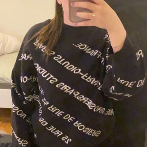 Tjocktröja från Gina Tricot  - Svart tjocktröja från Gina Tricot med texten ”Paris Studio France” och ”25 Rue de Rosiers” skrivet över den. Knappt använd och i fint skick! 💖