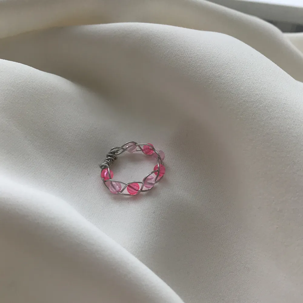 En egengjord ring av silvrig smyckestråd🥰 Den är inflätad med olika nyanserade rosa pärlor!           stl : S    Den är Nickel fri, Bly fri och Kadium fri🤩. Accessoarer.