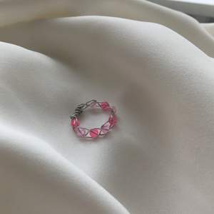 En egengjord ring av silvrig smyckestråd🥰 Den är inflätad med olika nyanserade rosa pärlor!           stl : S    Den är Nickel fri, Bly fri och Kadium fri🤩