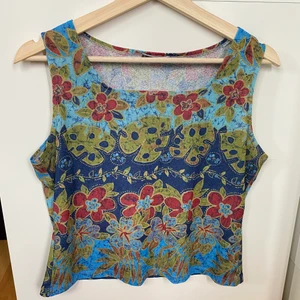 Blommig topp - Storlek: M/L. Plaggets längd 50cm, 48cm bredd. Strechigt tyg. Betalningsmetod: Swish. Frakt tillkommer postnord blå påse 45kr