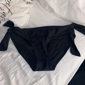 Svarta bikinitrosor strl 34  - Ett par svarta bikinitrosor i strl 34 från H&M, använda förr, knytningen är Fake den är bara där som detalj har ingen funktion. 