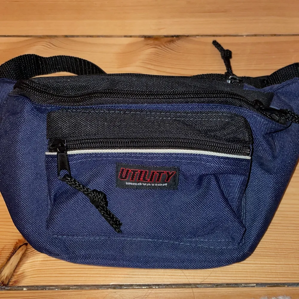 En eastpack midjeväska i blått och en svart väska med randigt axelband. Midjeväska från Utility innovation.. Väskor.