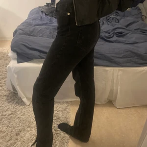 Svarta jeans med slit - Jättefina svarta mid-waist jeans från pull&bear med slit längst ner, storlek 38. Jättebra skick! Jag är 175cm och de går ner till skorna, köparen står för frakt :)