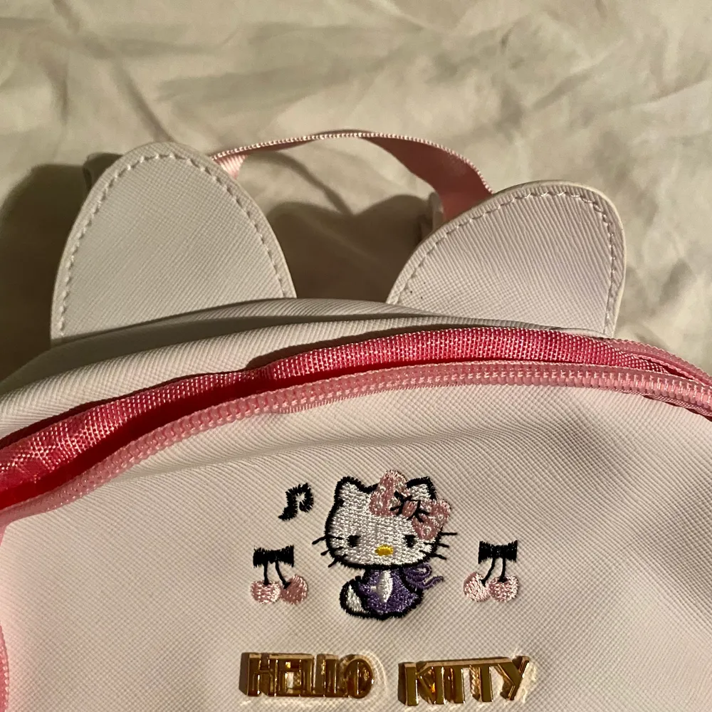 Söt vit liten hello Kitty ryggsäck. Ryggsäcken har rosa detaljer, hjärtan på dragkedjorna, små öron på toppen, och musik noter på fickan. Den har en inne ficka och två fickor på sidorna. Väskan är liten men inte för barn. Jag har massor med flera bilder så är du intresserad är det bara att fråga! Väskan är aldrig använd, jag säljer den just för den anledningen. Man kan få plats med A5 i den 🥰 . Laukut & Käsilaukut.