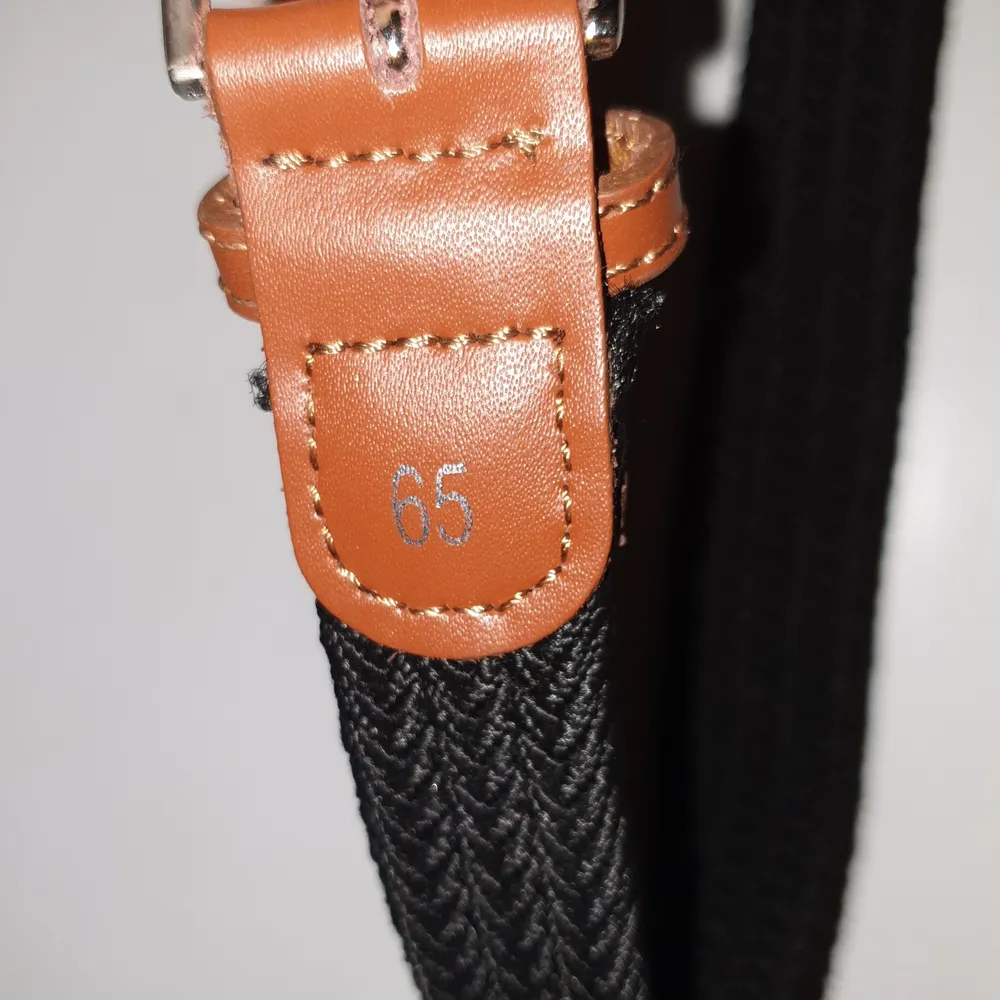 Ett svart och brunt stretchigt bälte. 65 cm långt.. Accessoarer.