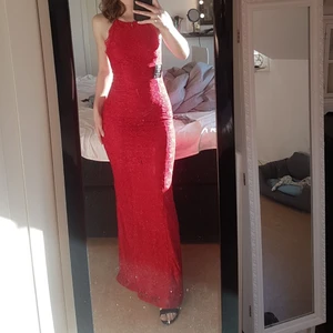 Röd balklänning  - Röd balklänning i spets från Nelly i storlek 34. Öppen rygg med knytning och med ett litet släp. Köpt för 899 och använd en gång 