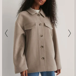Kort kappa från NA-KD - Intressekoll!!  En helt ny beige schacket från NA-KD i storlek 36. Säljer om jag får ett bra bud. Slutsåld på hemsidan!!Köparen står för frakten💕 Nypris:799kr