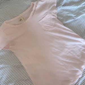 Ljusrosa T-shirt hollister  - En ljusrosa tshirt från Hollister med hål men det var så den köptes, strl XS men passar även Small och möjligtvis medium💕