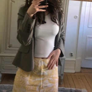 Gulblommig kjol - Gulblommig Åhléns kjol i storlek 38. Tyget är i bomull men i och med dess utsvävningar ger den en linnelik känsla i tyget. Kjolen är i väl bra skick.