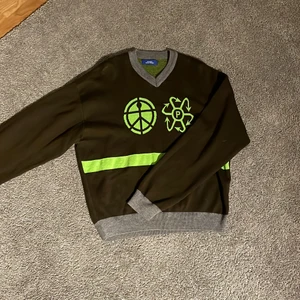 Stickad Rassvyet tröja - Plagget är köpt på plug me please för 1500 men saknar kvitta. Skick 10/10. Färg: Brun, Mörkgrå och Neongrön