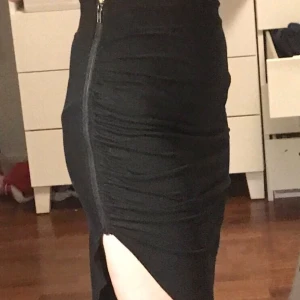 Svart sned kjol - Svart sneklippt kjol med en dragkedja på sidan. Materialet är väldigt stretchigt