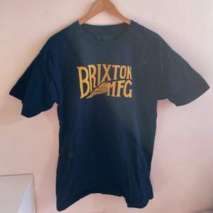 Marinblå t-shirt med gult tryck från märket Brixton säljer då den ej kommer till användning. Skicka dm vid frågor eller fler bilder💕. storlek: L