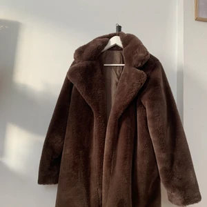 Brun fuskpäls - Längre tjock jacka i brun fuskpäls. Storlek XS-M OBS! Finns ett hål i en ficka