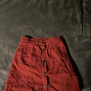 Röd kjol - Röd jeanskjol med små fickor och svarta metallknappar. Storlek 34 från monki. Inte använd ofta. Skriv om ni undrar nåt och vill köpa :)