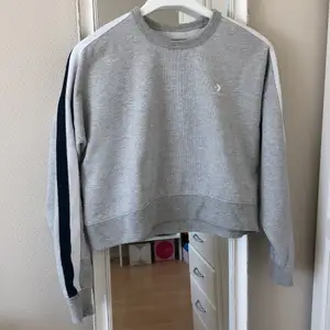 Supersnygg croppad sweatshirt från Converse med vita och mörkblå linjer på ärmarna. Aldrig använd! Budgivning börjar på 150 kr 