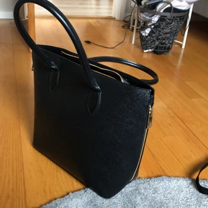 Svart skinnväska  - En svart väska i skinn med guld dragkedjor på sidorna och ett inuti väskan. Nästan helt oanvänd, använd knappt 2 gånger.