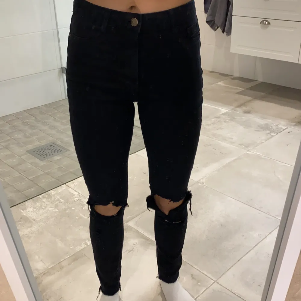 Svarta skinny mid waist jeans från Gina Tricot. Modell namn på byxorna ”Molly”. Hål på knäna och lite sådär ”söndrigt” nere vid ankeln (vet inte vad det kallas för).. Jeans & Byxor.