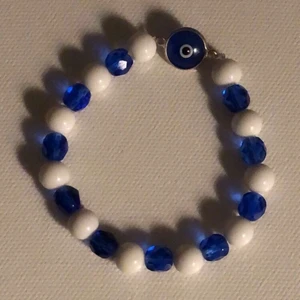 Armband - Coolt pärlat armband med ögliknande symbol. Bandet är elastiskt!