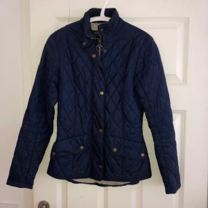 Barbour jacka - Tunn dunjacka från Barbour i marinblå storlek 34. Köpt för ett par år sedan. Fortfarande i hyfsat bra skick.  Säljes för 200 kr.
