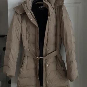 Zara jacka - Jätte snygg jacka inköpt under vintern 2020, i super bra skick men som inte längre används. Köptes för runt 900kr. Super snygg beige färg med låtsas päls runt luvan och bälte kring midjan. Svart ”päls” inuti jackan!