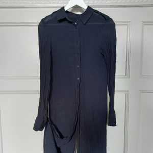 lång svart skjorta - en svart lång skjorta i ett mjukt tyg. skjortan är unikt skuren och går isär där bak. storlek s. LÄNGD: 112 cm. sparsamt använd, fint skick. tyget är tunt och lite texturerat.                                                                        jag möts upp i Malmö, annars betalar köparen en mindre summa för frakt. DMa för frågor/detaljer osv. 💌