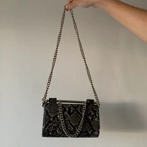 Liten väska från Zara - En liten ”plånboks-väska” med lång tillhörande kedja, går att vika in så den blir kortare (första bilden). Jättecoolt ormskinnsmönster och har massa bra fack invändigt för kort och dylikt. I princip aldrig använd. FRAKT tillkommer från 66kr. 