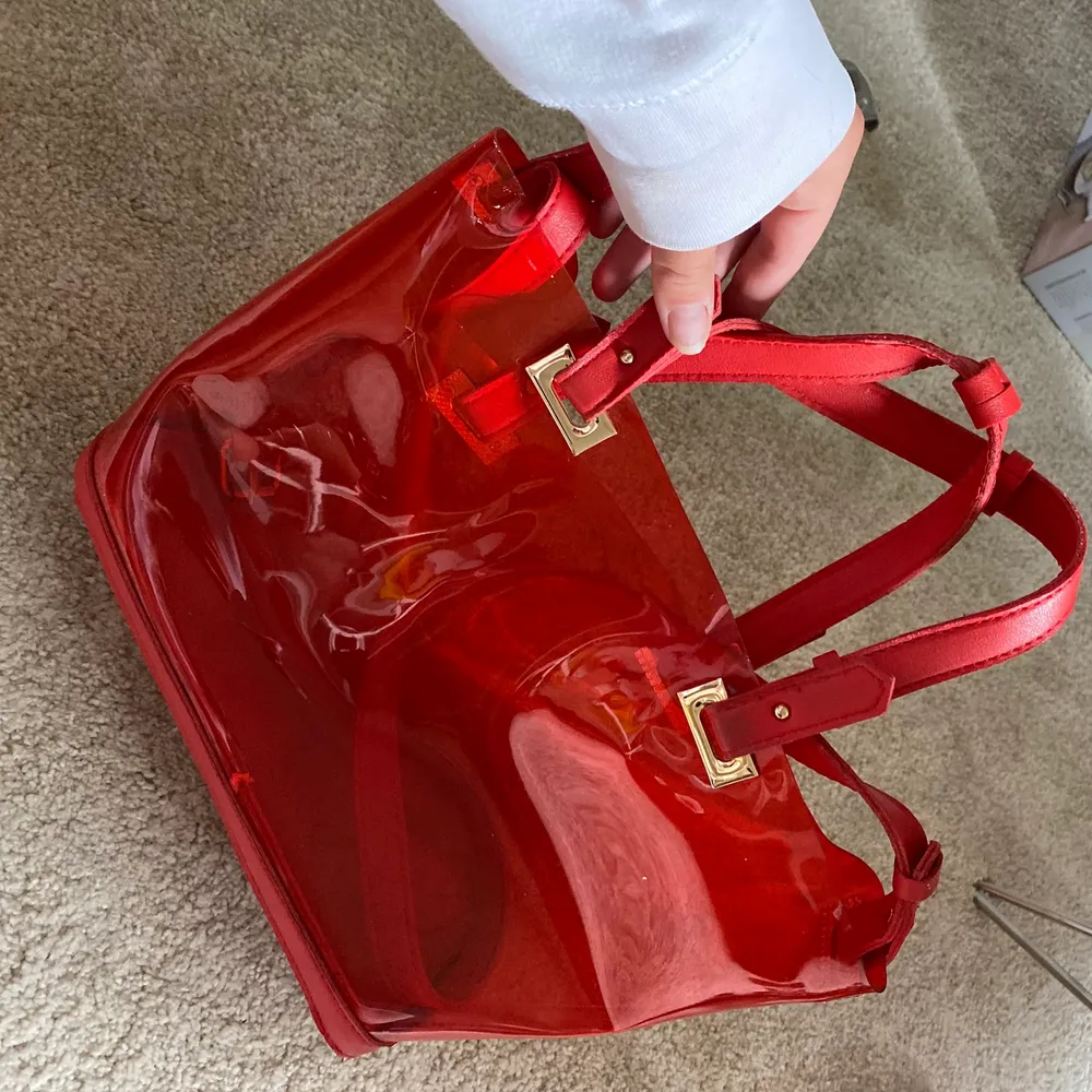 Hej säljer denna snygga röda väska som är genomskinlig I plastmaterial. Väskor.
