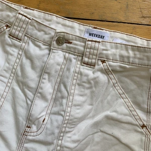 VITA CARGO JEANS - Vita cargo jeans från Weekday i storlek 36. Beige/bruna sömmar som ger en mer skatig look. Något korta i längden så passar ej någon som är lång.