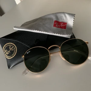 Rayban Solglasögon i nyskick - 11 månader gamla Rayban solglasögon i metall med originalfodral och putsduk. Glasögon är UV skyddade med mörk toningsgrad (katergori 3). Glasögon är inte användna mer än 10 gånger och är i storlek 50. Kund står för frakt.