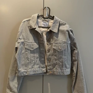 Zara jeans jacka - Oanvänd Zara, grårutig jeansjacka i kort modell. Väldigt fin till våren nu och cool modell men säljer då den inte kommer till användning!