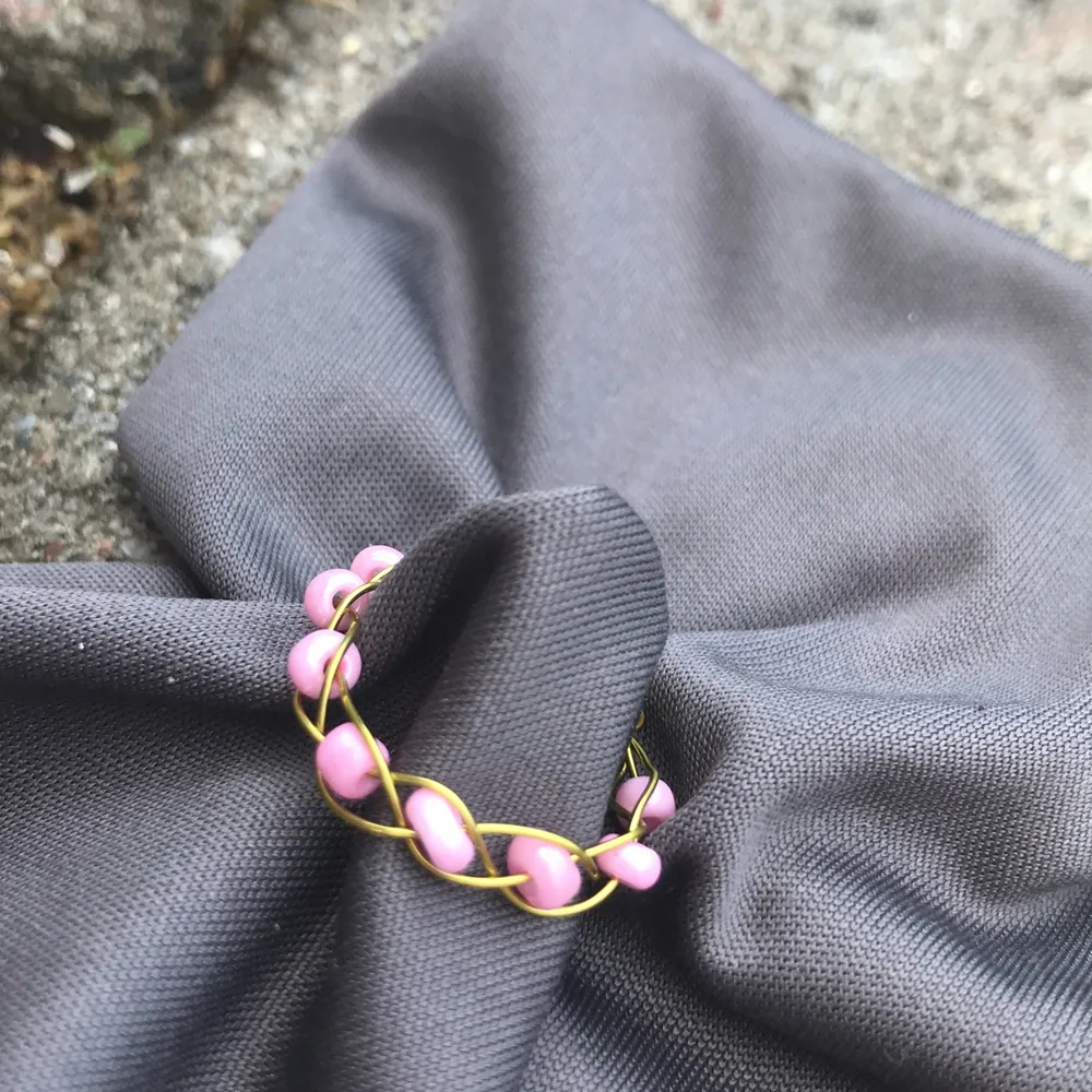Flätad ring i guld färgad smyckes tråd, med rosa pärlor.                 stl: S-XS.                                                     Den är Nickel fri, Bly fri och Kadium fri!!!. Accessoarer.