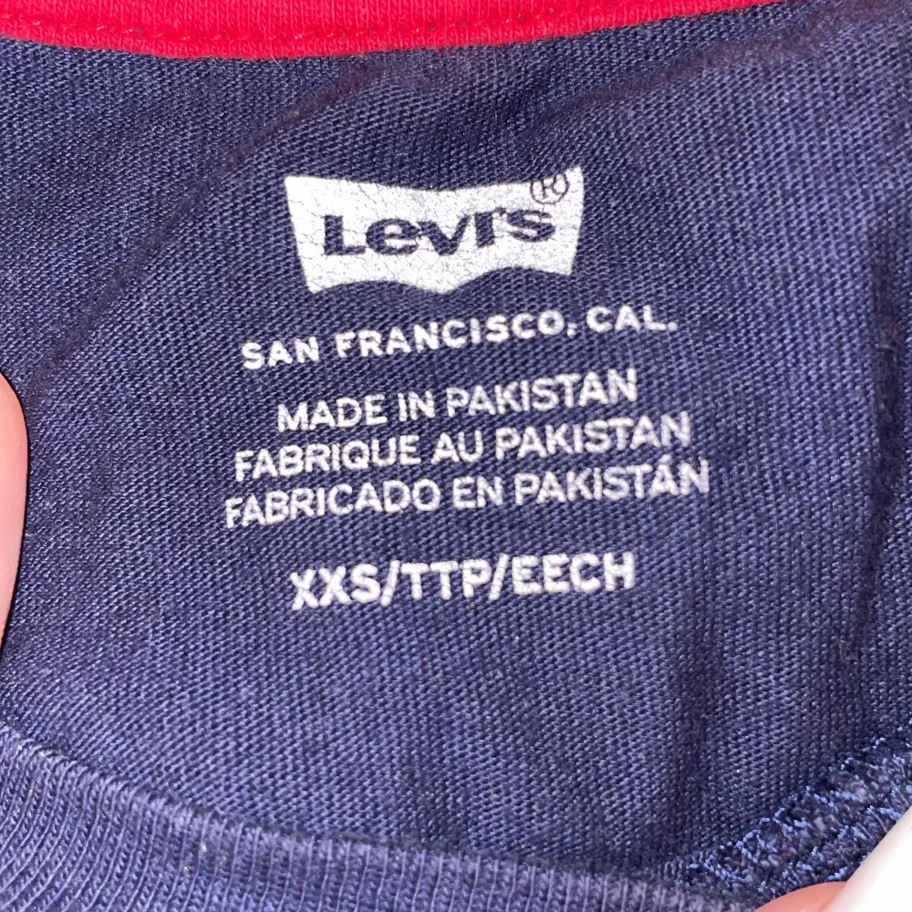 En blå vit och röd tröja med texten ”Levi’s”. T-shirts.