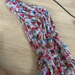 Halsduk  - En tunn halsduk som är vit med blommor i olika färger. Använd någon gång men är i väldigt fint skick. Denna är i 100% polyester. Köparen står för frakten. 