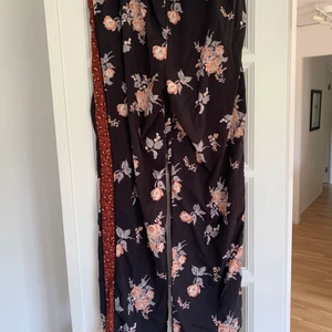 Fladdriga byxor  - Byxor med blommor på och en röd kant på sidan. Har använt en gång så dom är i bra skick. 