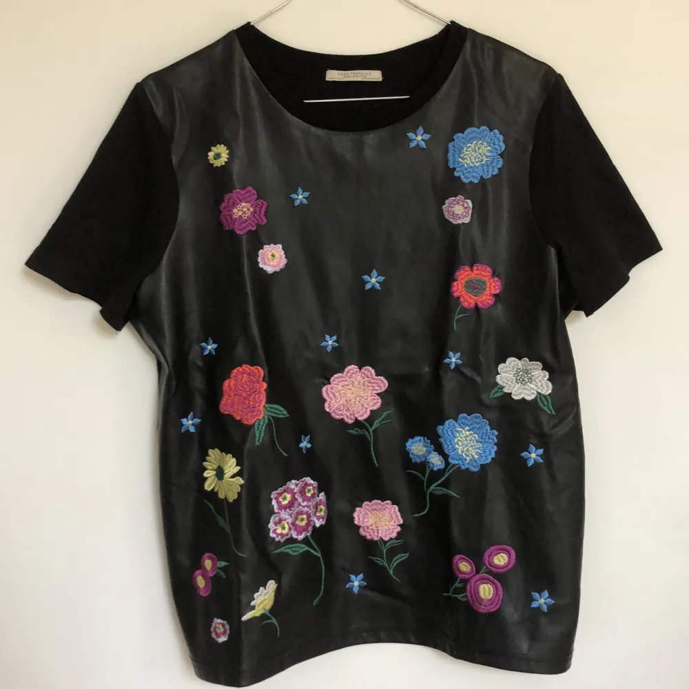 Supercool skinn t-shirt från Zara med broderade blommor i olika storlekar och färger. Framsidan är i läderimitation medans armarna och baksidan är gjort av tyg. . T-shirts.
